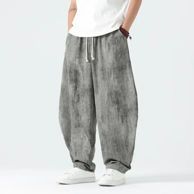 Person wearing gray baggy pants and white shoes on a light gray background