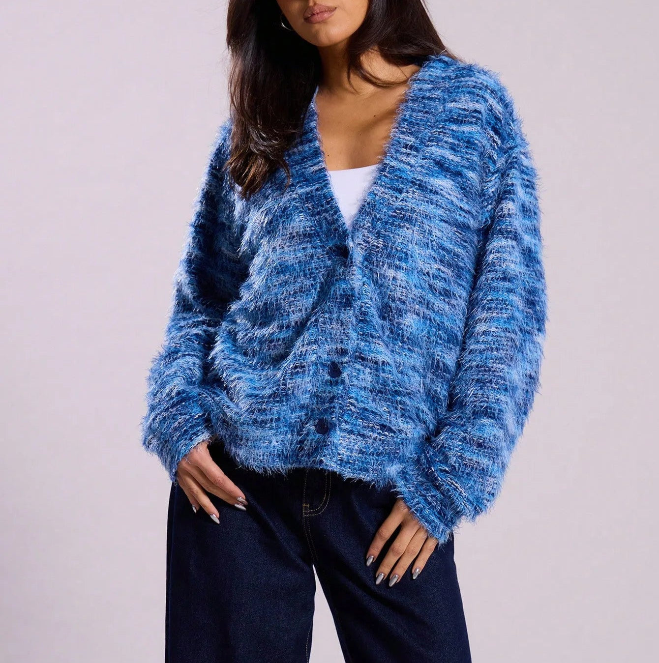 Woman wearing a blue knitted cardigan against a plain background