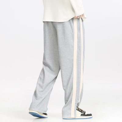 Gray sweatpants with a white top and black shoes on a white background