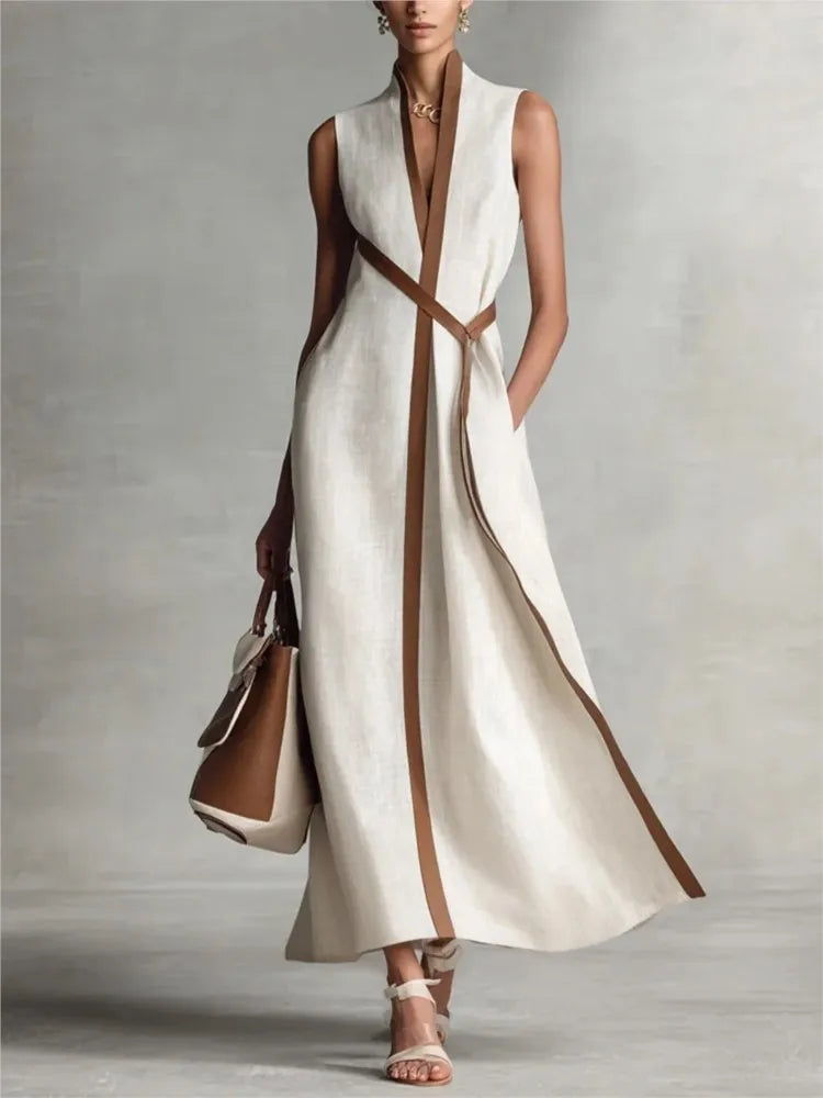 Woman wearing a long white dress with brown accents against a gray background