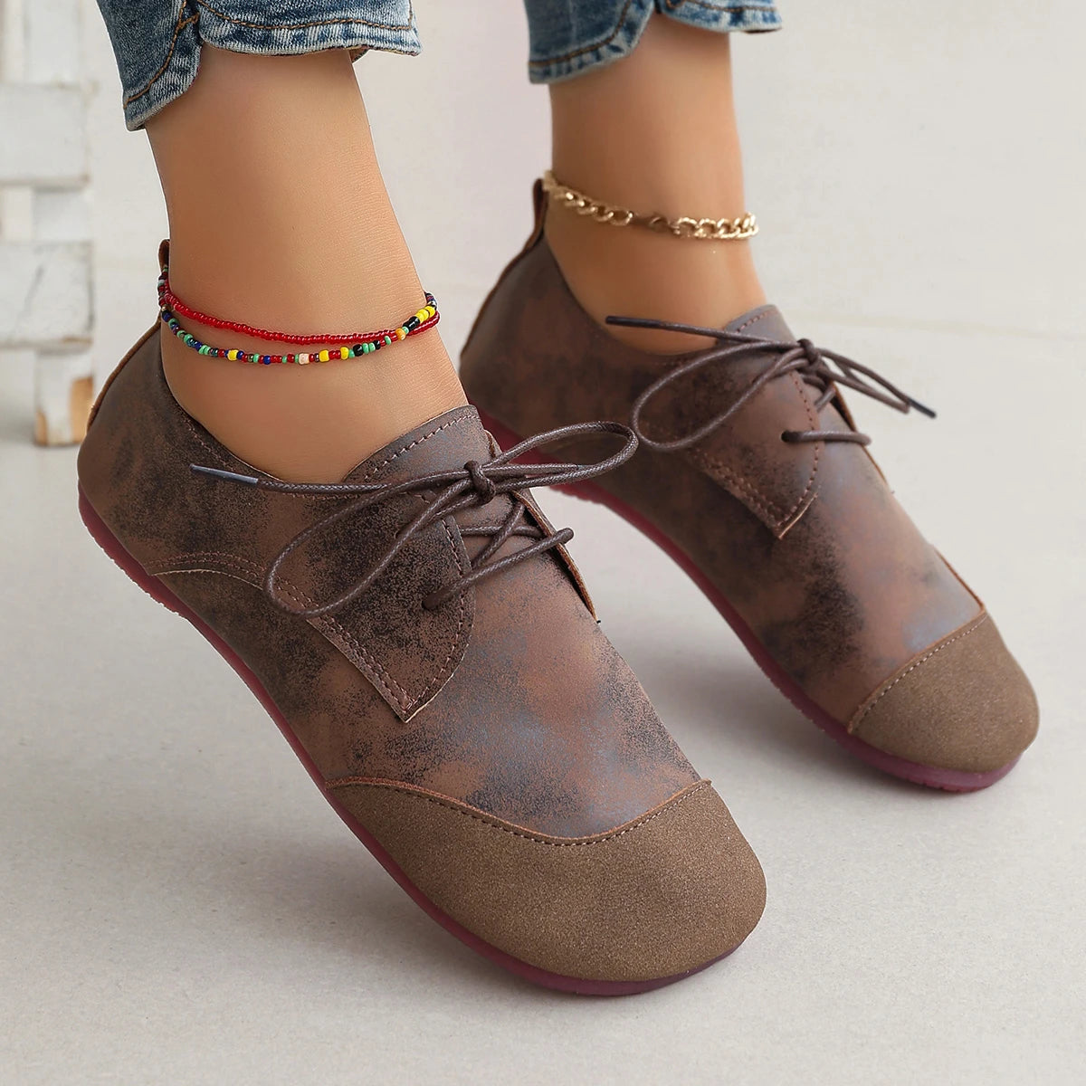 Brown leather shoes with lace-up design worn by a person on a light background