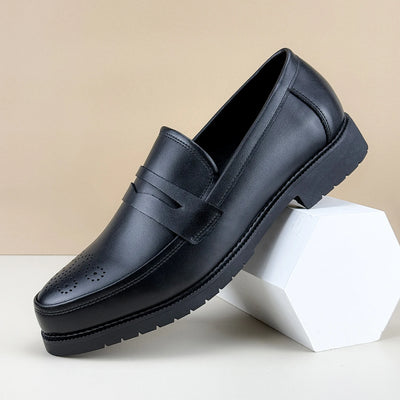 Black leather loafer shoe on a beige background