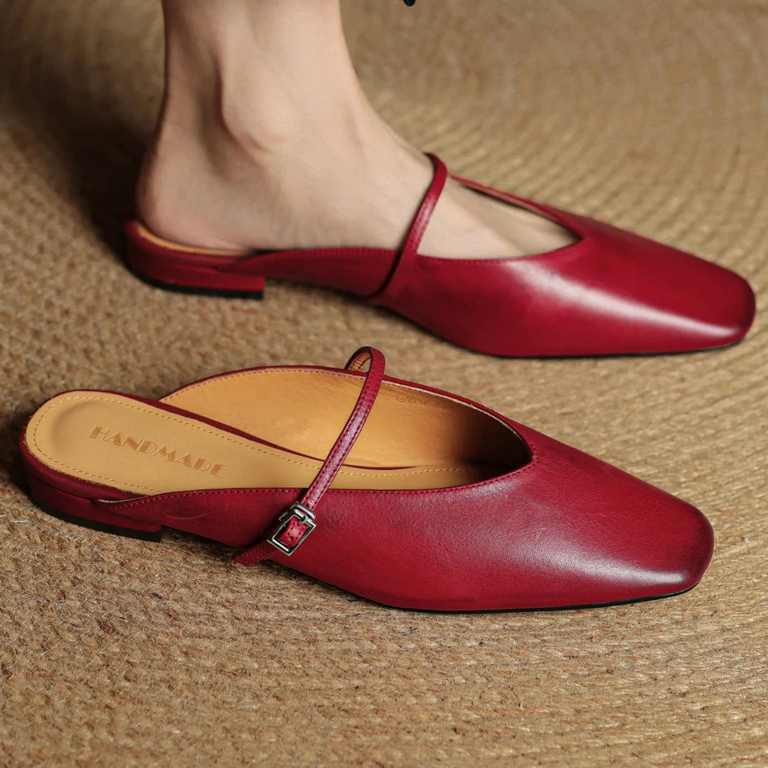 Red leather shoes with a strap on a textured surface