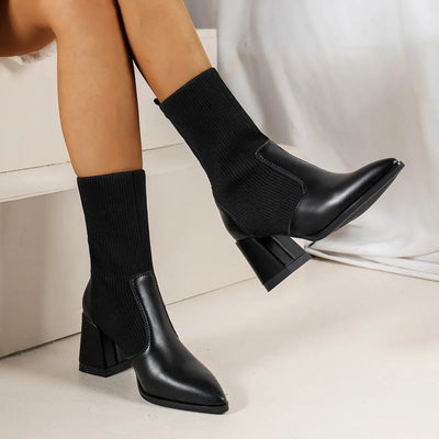 Black sock boots worn by a person on a light background