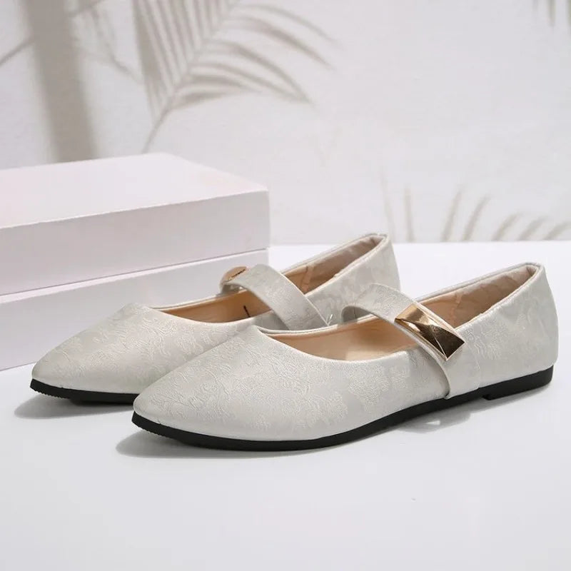 Pair of white flat shoes with a strap on a light background