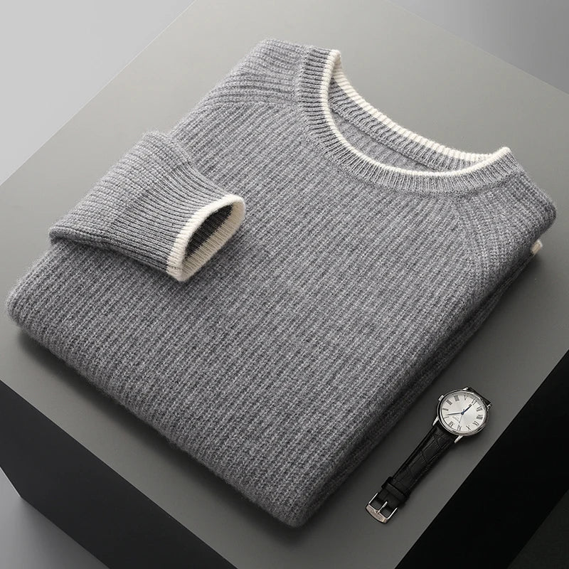 Folded gray sweater with a watch on a dark surface