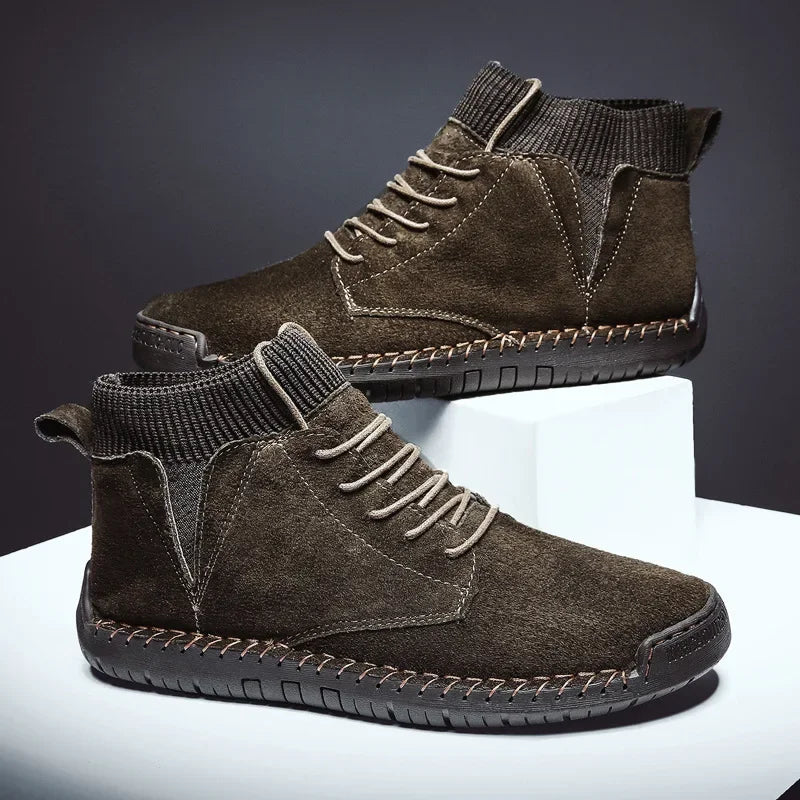 Pair of brown suede boots on a reflective surface with a dark background