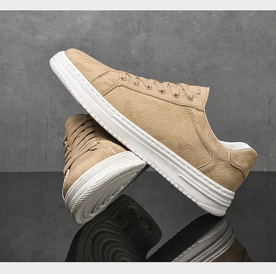 Beige sneakers with white soles on a reflective surface with a gray background