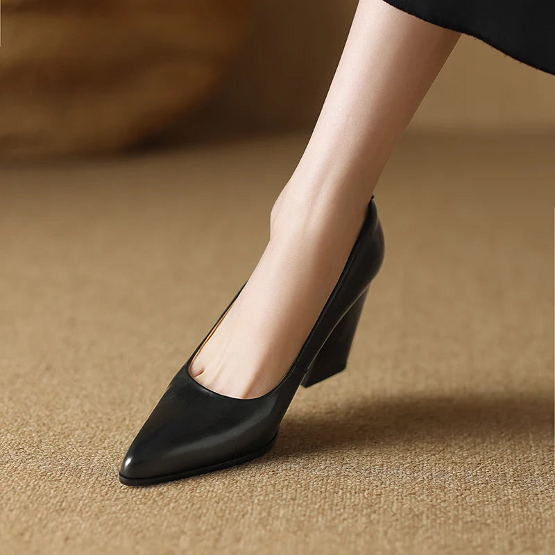 Black high-heeled shoes worn by a person on a beige surface
