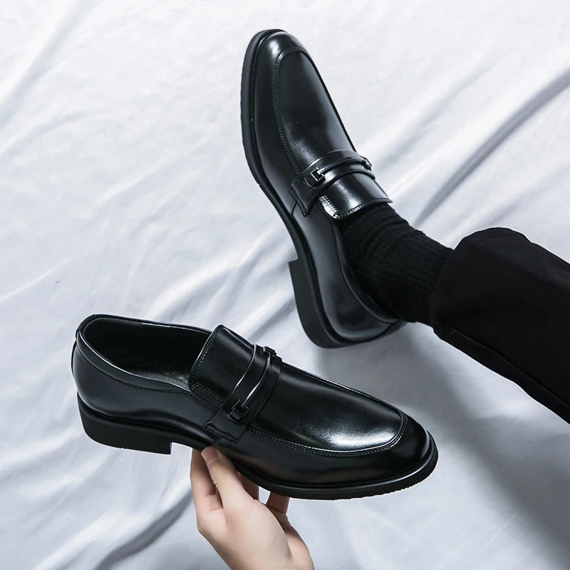 Black dress shoes being held against a white background