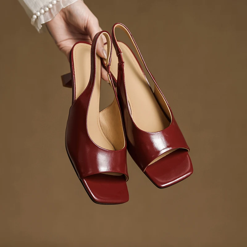Red high-heeled shoes held by a hand against a brown background