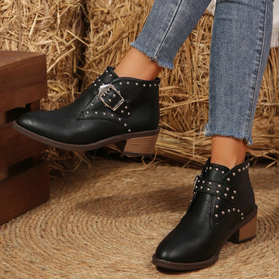 Black studded ankle boots worn with jeans on a rustic background