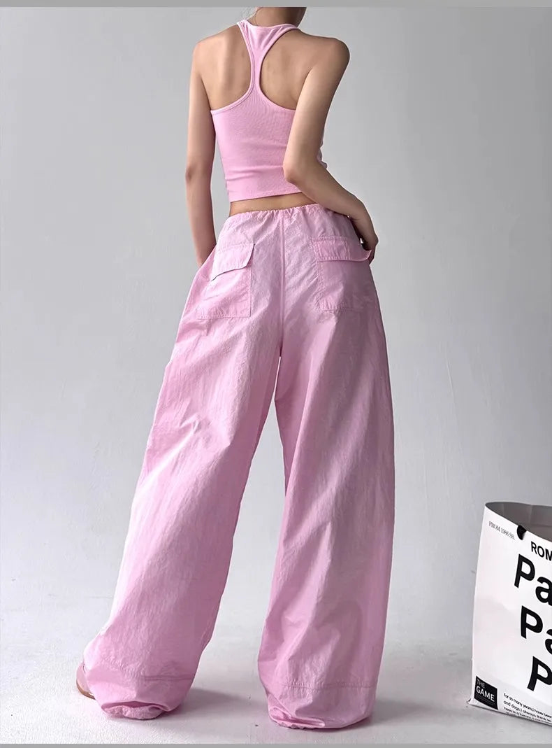 Person wearing a pink outfit with wide-leg pants and a crop top on a plain background