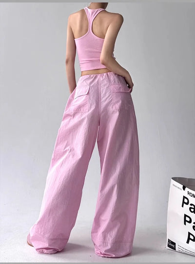 Person wearing a pink outfit with wide-leg pants and a crop top on a plain background