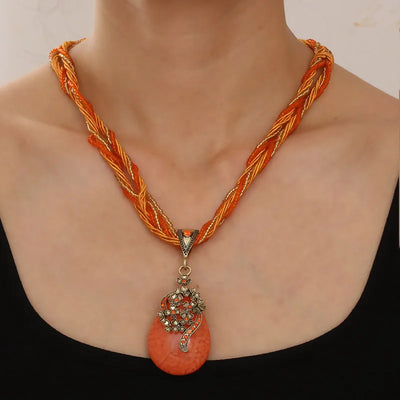 Necklace with braided design and coral pendant on a plain background