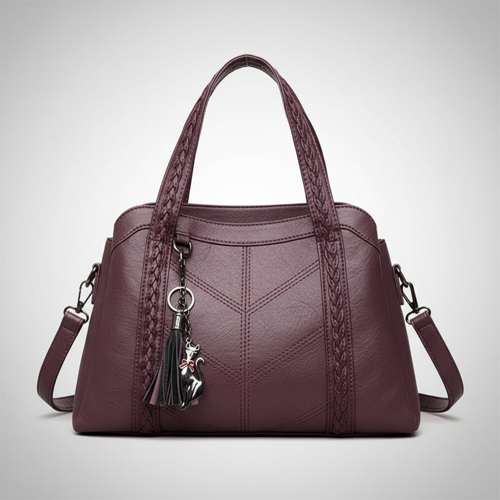 Purple handbag with braided handle and charm on a white background