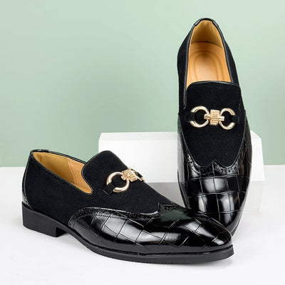 Black loafers with gold accents on a light green background