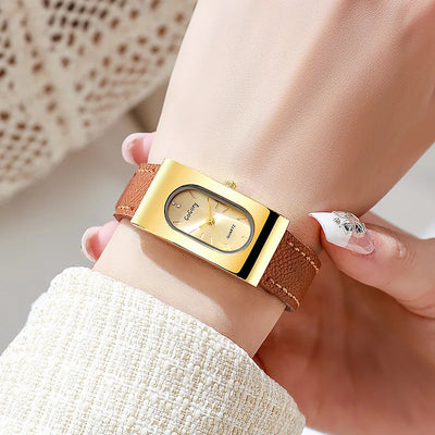 Gold wristwatch with brown leather strap worn on a wrist