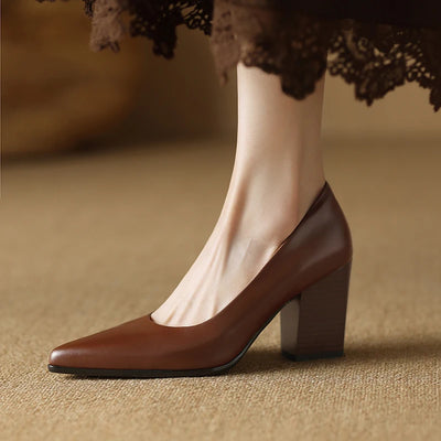 Brown leather shoe worn with a lace-trimmed dress on a textured surface