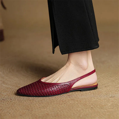 Red flat shoe worn with a black pant leg on a beige background