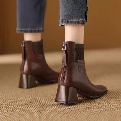Brown ankle boots worn with rolled-up jeans on a textured surface