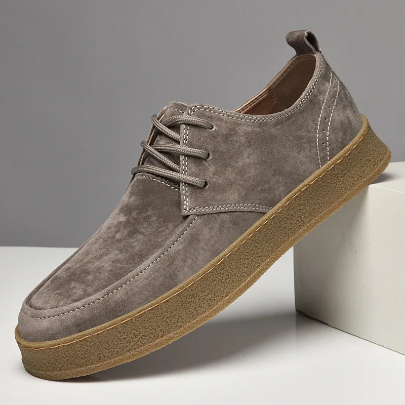Gray suede shoe with brown sole on a gray background