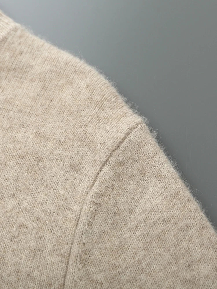 Close-up of a beige sweater sleeve against a gray background