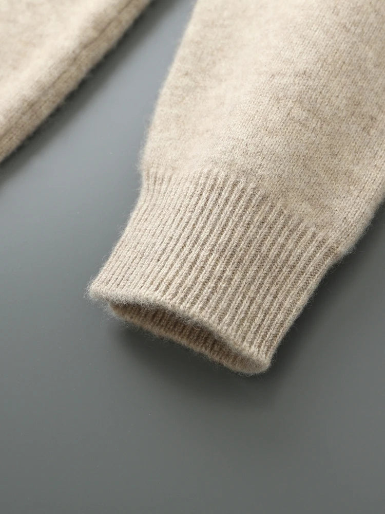 Close-up of a beige knitted sweater sleeve on a gray background