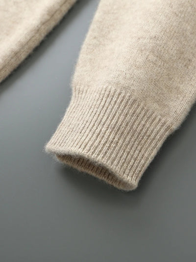 Close-up of a beige knitted sweater sleeve on a gray background