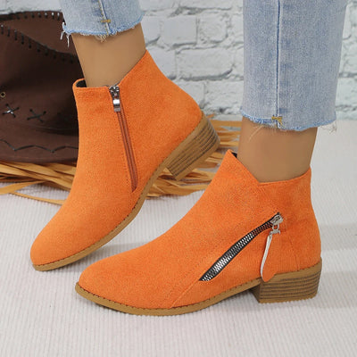 Orange ankle boots with zippers worn by a person, against a neutral background.