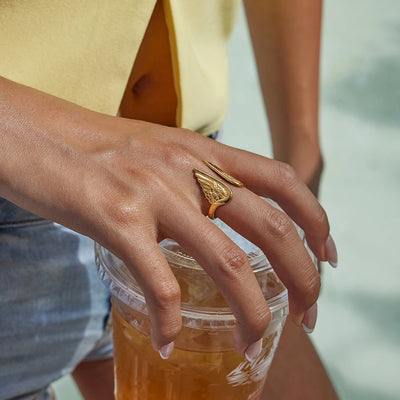 Hand holding a jar of honey with a gold ring on a blurred background
