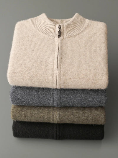 Stack of folded sweaters in beige, gray, and black on a gray background