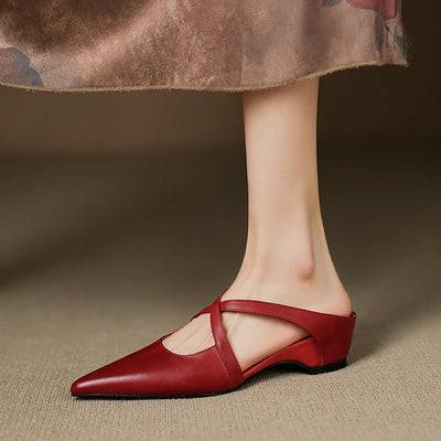 Red leather shoe worn by a person on a neutral background