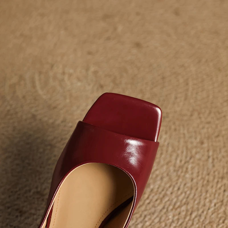 Maroon high-heeled shoe on a textured brown surface