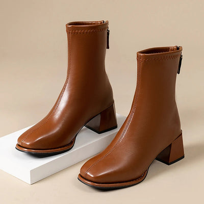 Pair of brown leather ankle boots on a beige background