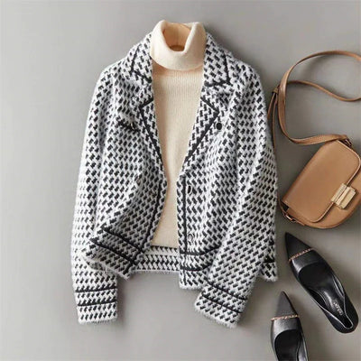 Houndstooth patterned jacket, beige turtleneck, brown handbag, and black shoes on a gray background