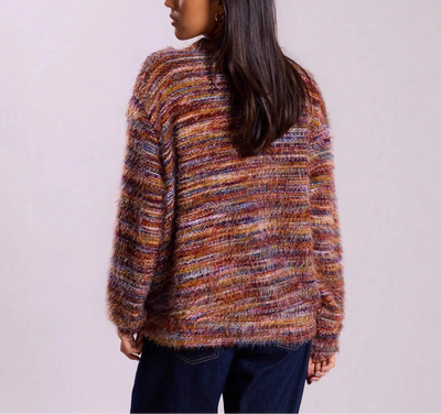 Person wearing a multicolored sweater against a plain background