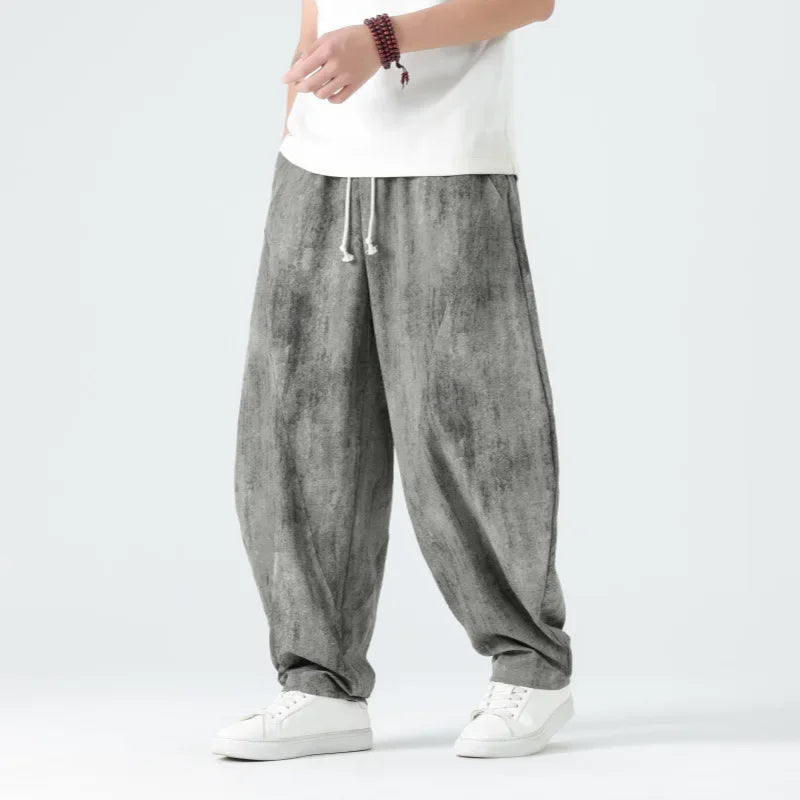 Person wearing gray baggy pants with a white shirt on a light gray background