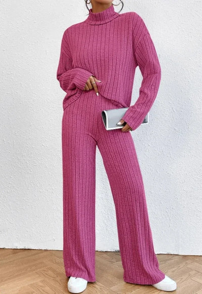 Person wearing a pink ribbed sweater and pants set against a white background