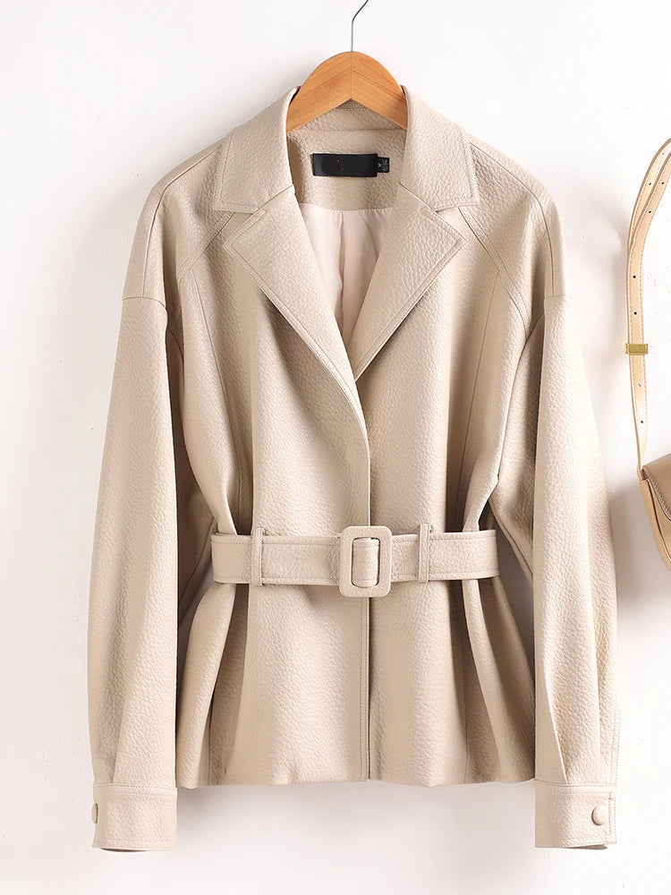 Beige trench coat with a belt on a wooden hanger against a white background