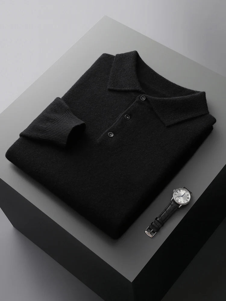Folded black polo shirt on a gray surface with a black watch.