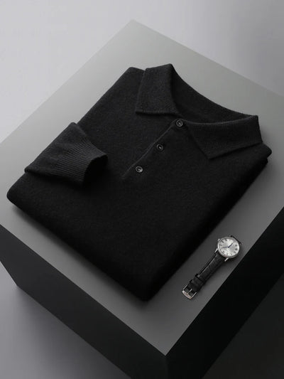 Folded black polo shirt on a gray surface with a black watch.
