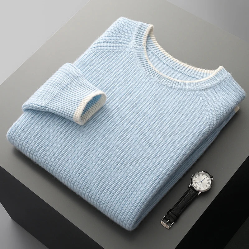 Folded light blue sweater on a dark surface with a watch beside it