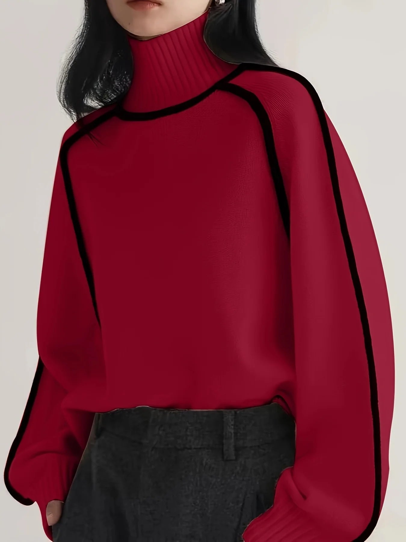 Red sweater with black trim worn by a person on a plain background