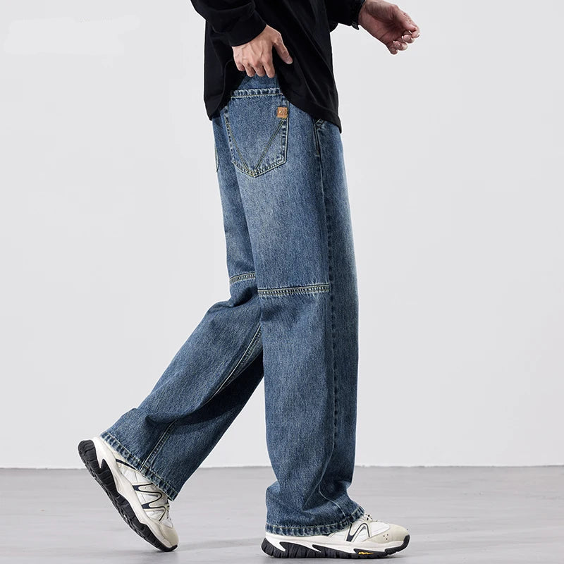 Person wearing blue jeans and white sneakers on a plain background.