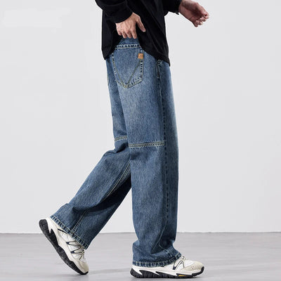 Person wearing blue jeans and white sneakers on a plain background.