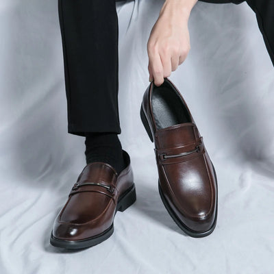Brown dress shoes being worn with black socks on a light gray background