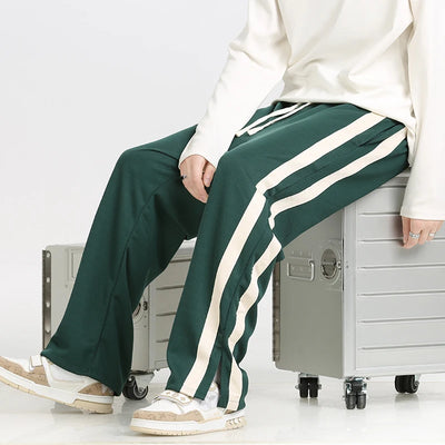Person wearing green pants with white stripes sitting on a metal locker.