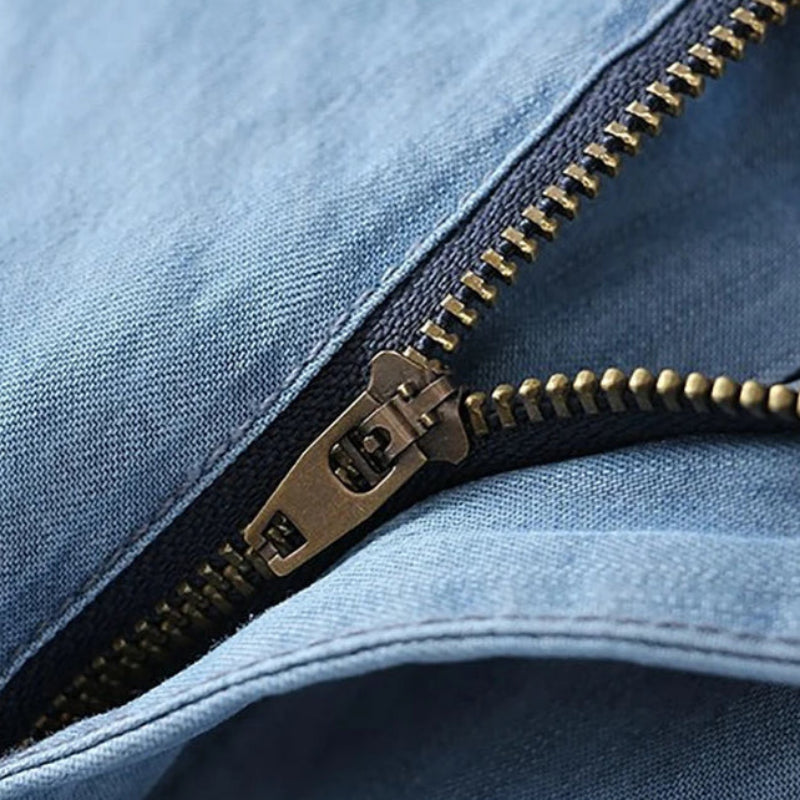 Close-up of a gold zipper on blue denim fabric