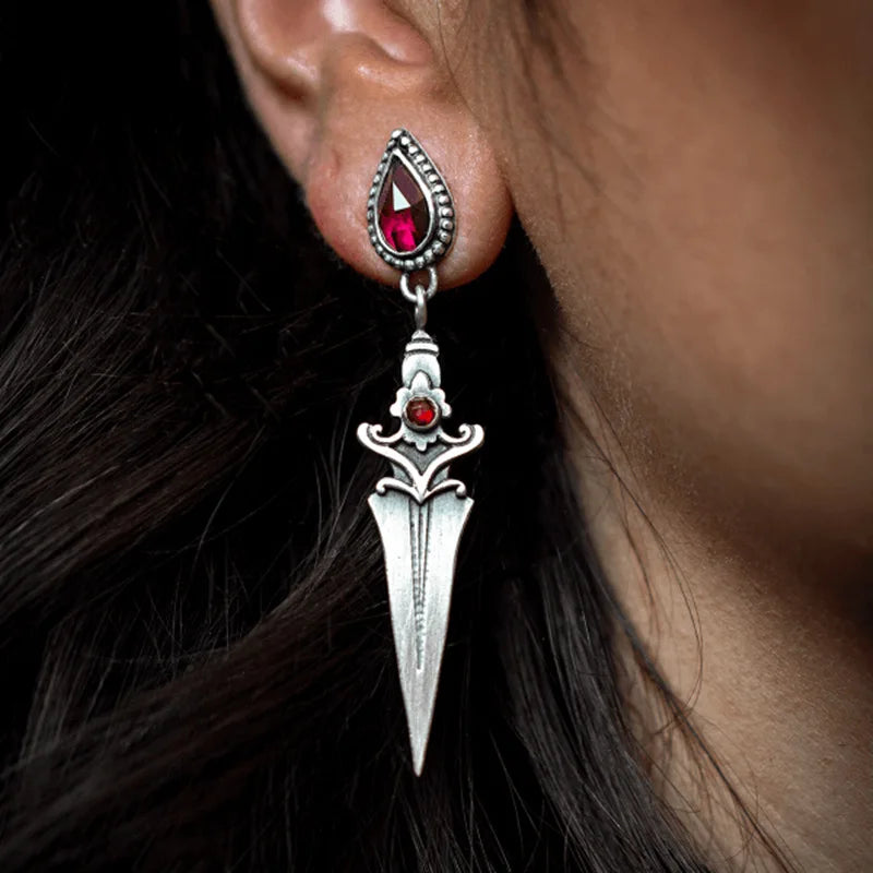 Earring with a red gemstone and silver design on an ear, with dark hair in the background.